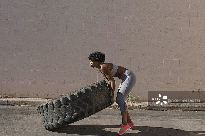 女人靠墙举轮胎锻炼图片素材