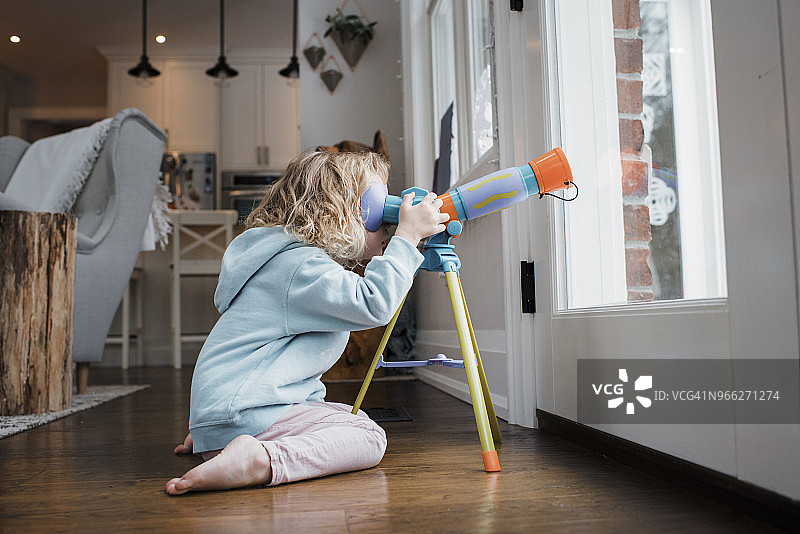 女孩跪在家门口用望远镜观察的侧视图图片素材