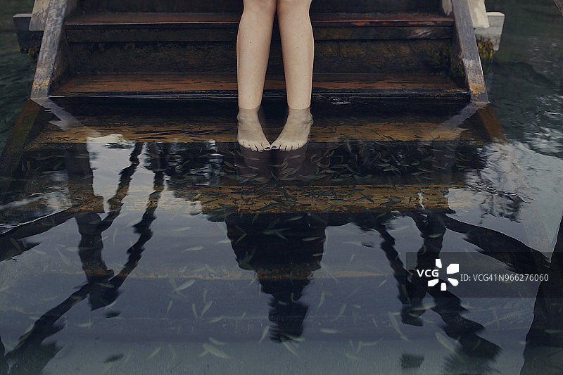 女子在湖中台阶上做鱼疗的下半身照片图片素材