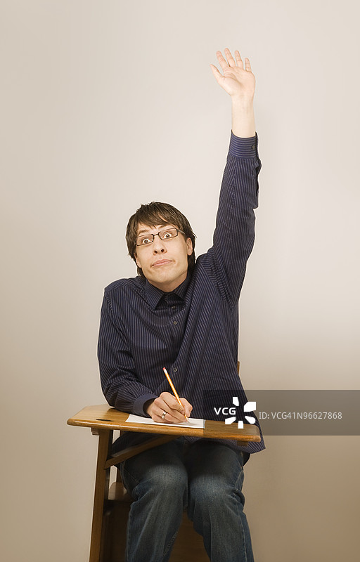 坐在课桌上的男孩举手图片素材
