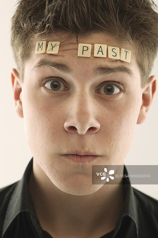头上放着字母拼块拼成“我的过去”的男人图片素材