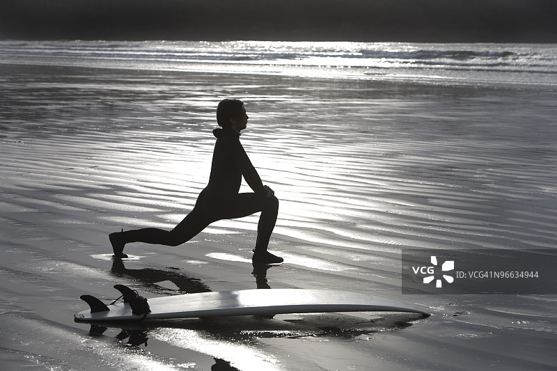 冲浪者在海滩上伸展身体图片素材