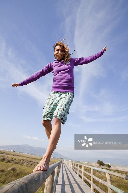 年轻女性赤脚在木结构上保持平衡图片素材