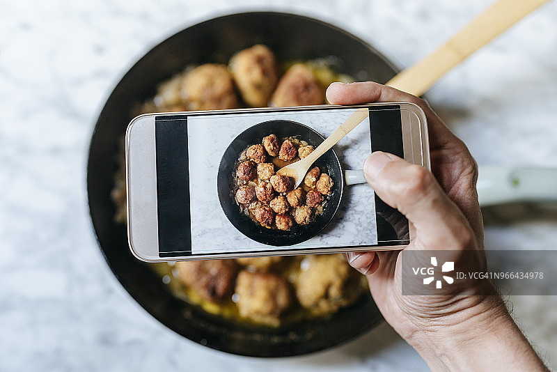 男人用智能手机拍摄肉丸的特写图片素材