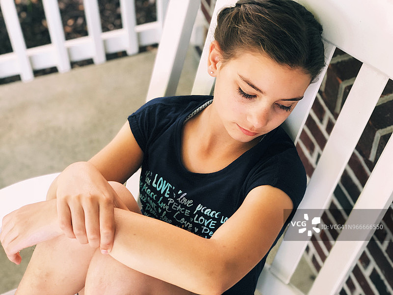 坐在前廊摇椅上的11岁女孩（高角度）图片素材