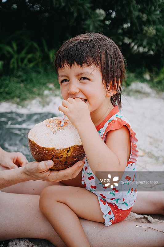 可爱的小女孩在冲绳海滩喝椰子汁图片素材