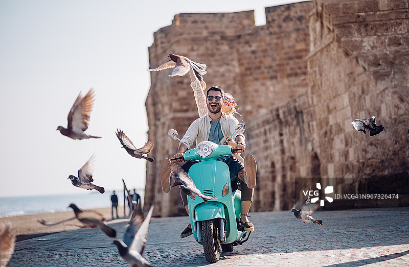 年轻情侣在欧洲古镇骑滑板车图片素材