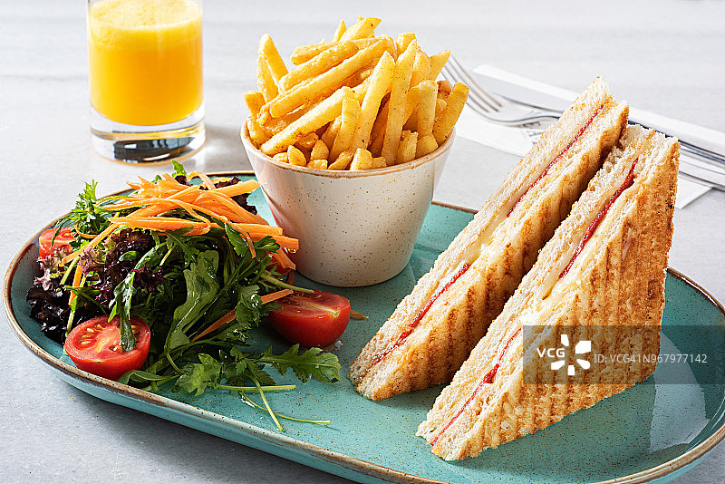 俱乐部三明治配薯条、沙拉和橙汁图片素材