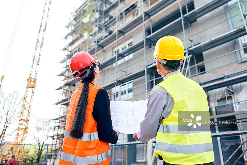 工程师与建筑师在建筑工地查看蓝图图片素材