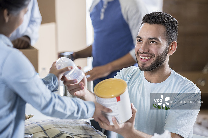 年轻妈妈在食品捐助活动中收到婴儿配方奶粉图片素材
