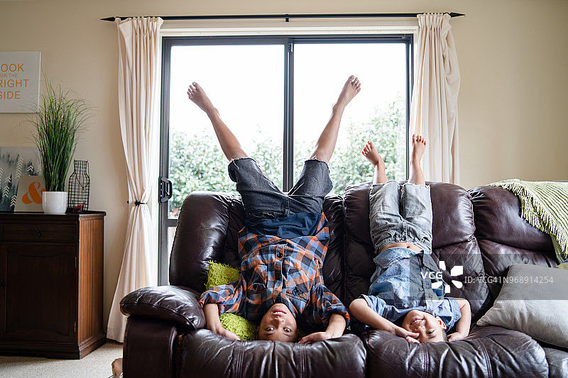 孩子们在家中客厅的沙发上倒立玩耍图片素材