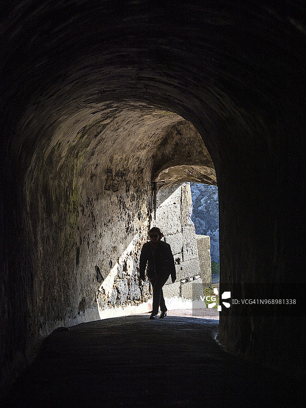 女人走在黑暗的地下隧道里走向光明，葡萄牙亚速尔群岛特塞拉岛图片素材