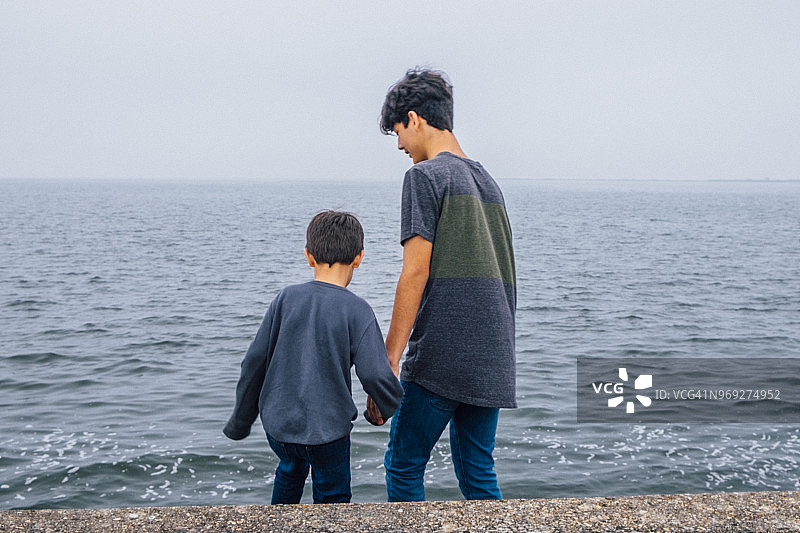 青少年男孩和弟弟在水边图片素材