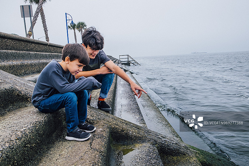 青少年男孩和弟弟在水边图片素材