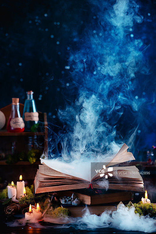 带有神秘烟雾的魔法书，女巫的工作场所与药水和草药，深色背景上的打开的书图片素材
