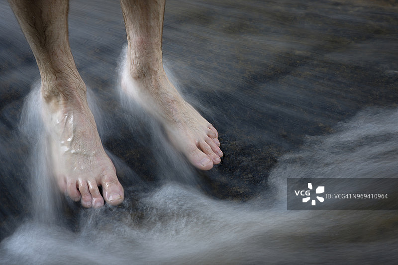 男人赤脚站在河石上的流水中，南非皇家纳塔尔龙山图片素材