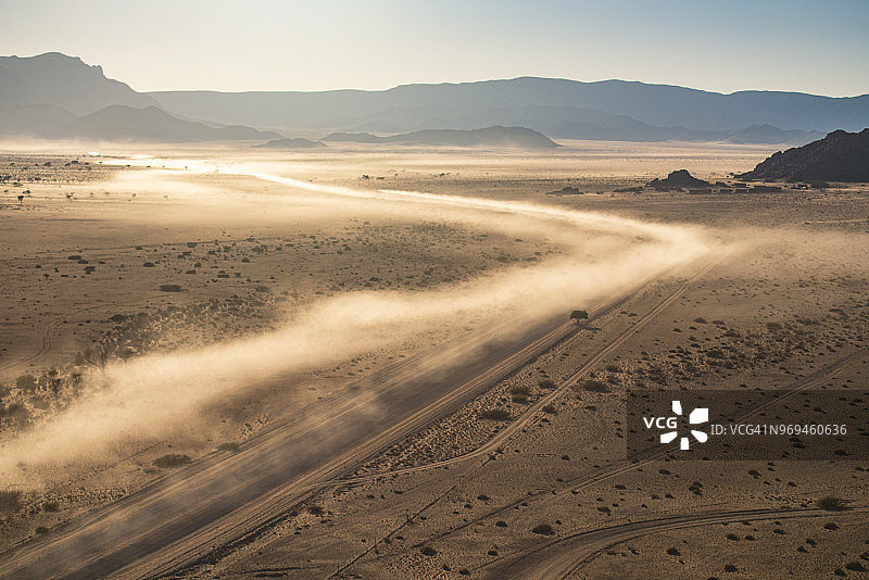 日出时分尘土飞扬的土路。鸟瞰，纳米比亚。图片素材