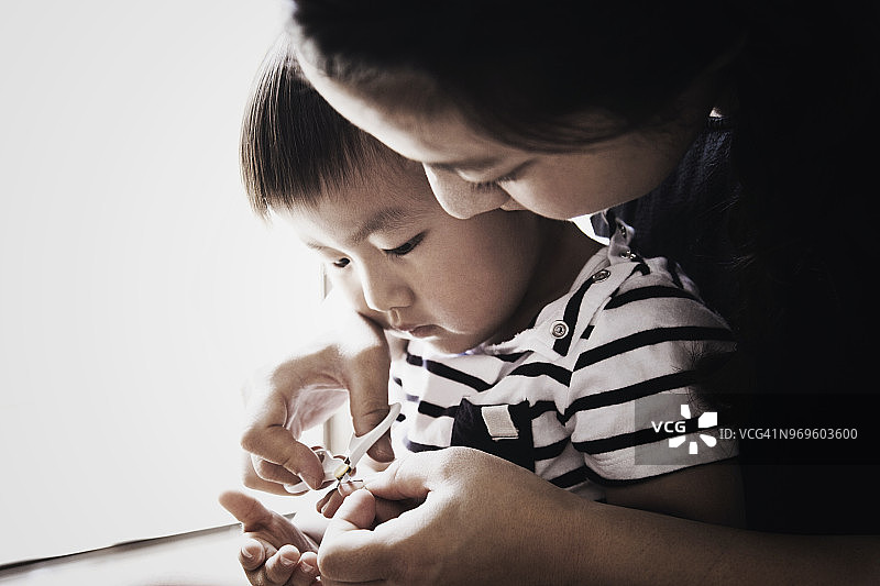 母亲在家给男孩剪指甲图片素材