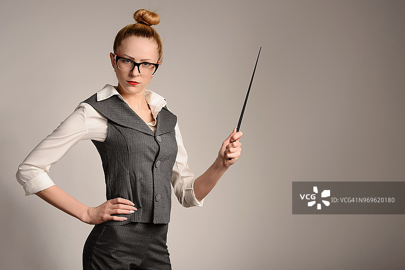 穿着西装，手持教鞭的严肃苗条女教师图片素材