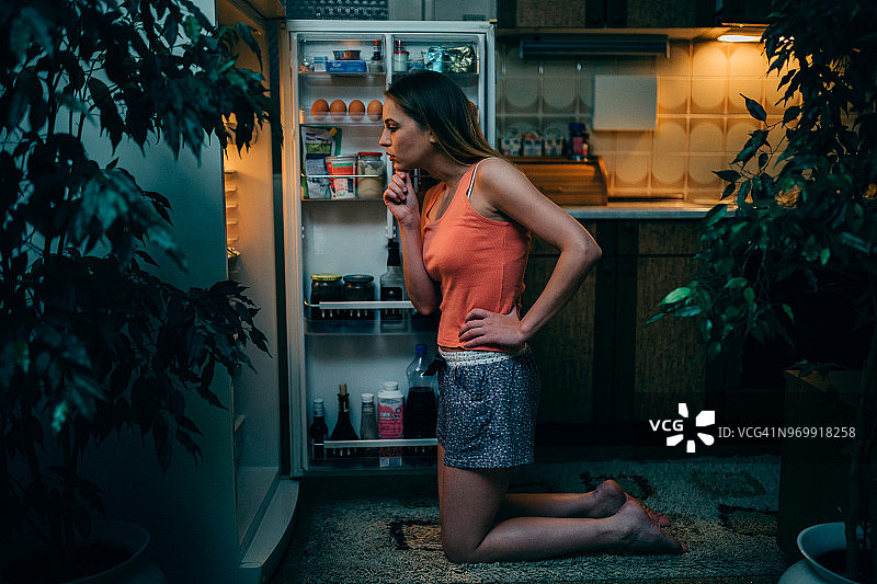 深夜在冰箱里寻找食物的年轻女人图片素材