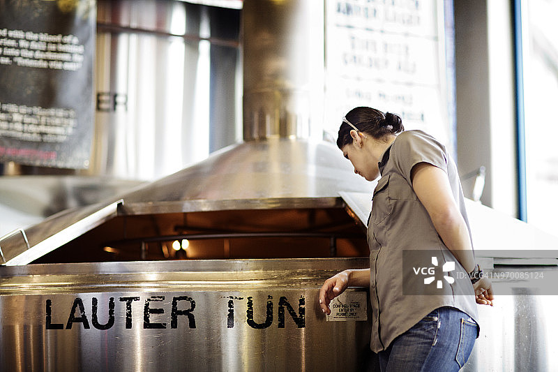 女人在啤酒厂检查储罐中的啤酒图片素材