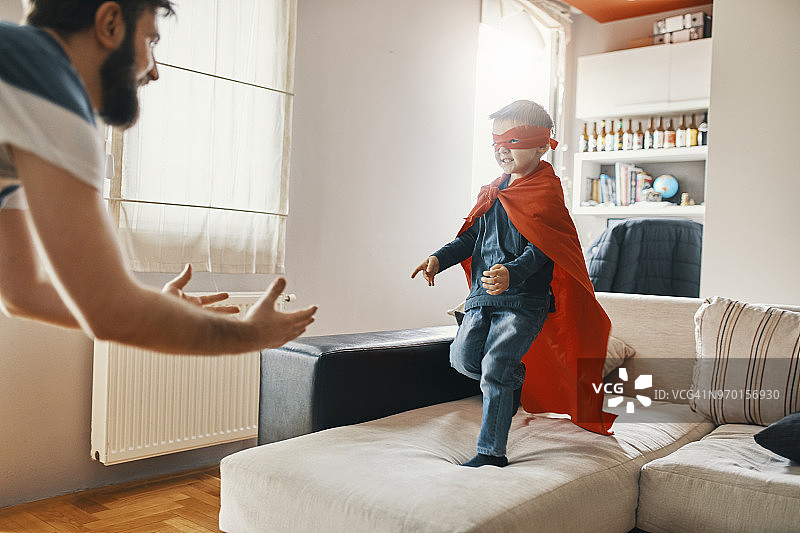 父亲在家中和打扮成超级英雄的小儿子玩耍图片素材