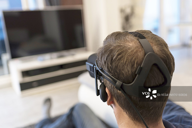 戴VR眼镜看电视的男子图片素材