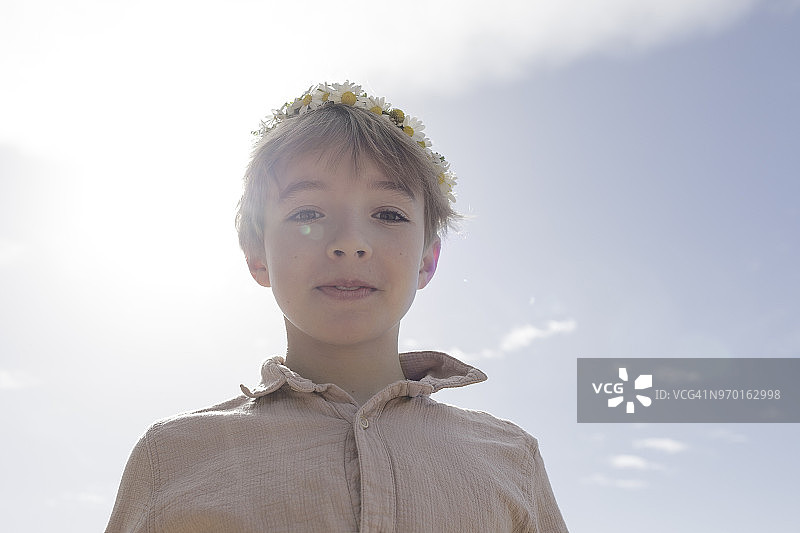 逆光下戴着花的男孩肖像图片素材