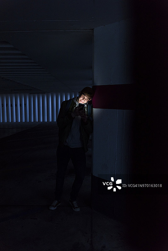 微笑男人在停车场看发光的智能手机图片素材