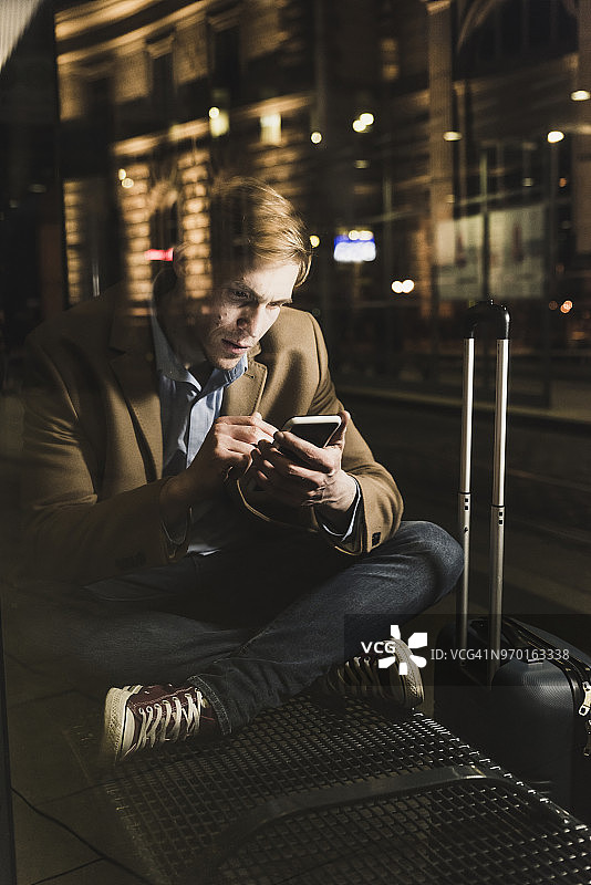 在夜晚电车站使用手机的商人图片素材