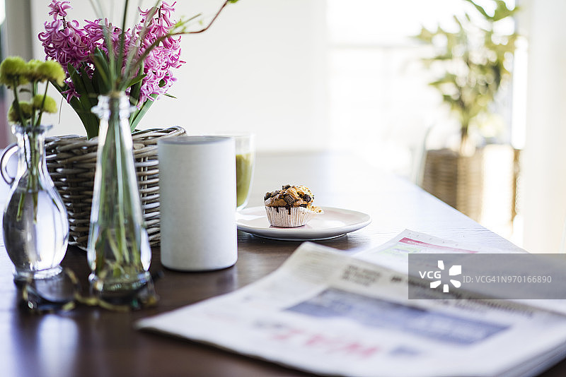 报纸、花瓶、扬声器和松饼在桌子上图片素材