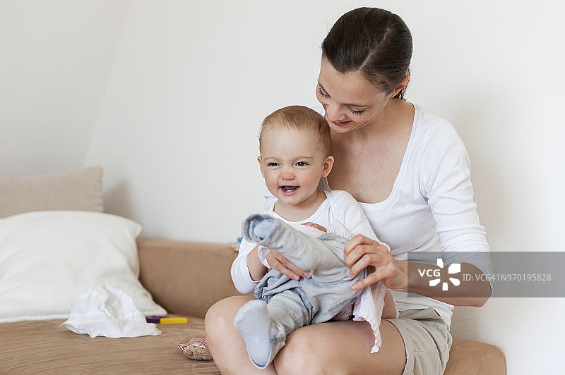 母亲在家给宝宝穿裤子图片素材