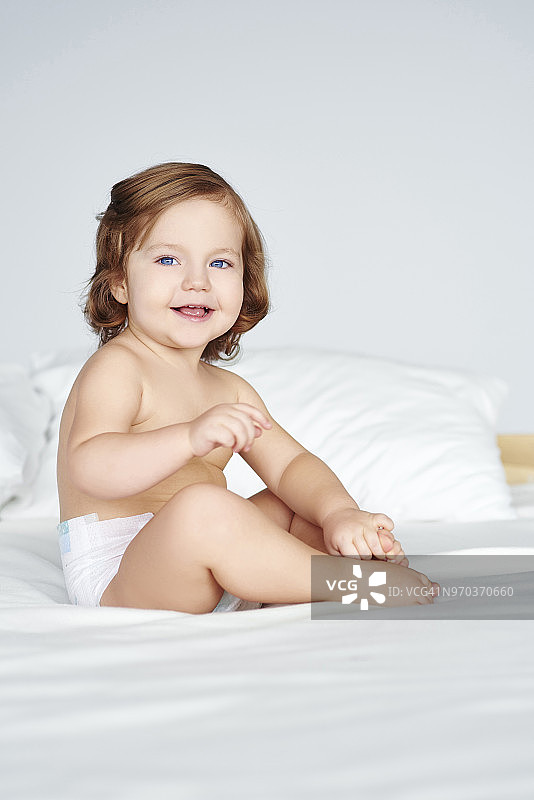 坐在床上的快乐女婴。德比察，波兰图片素材