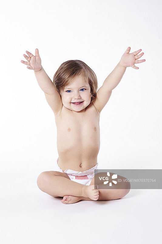 盘腿坐着，举起双手的小女孩，工作室拍摄图片素材