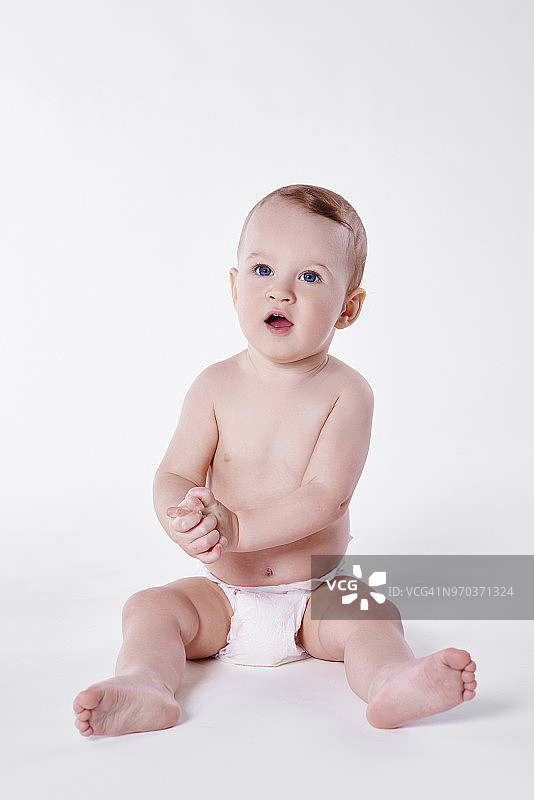 穿着白色尿布，双手放在身边的男婴，影棚拍摄图片素材