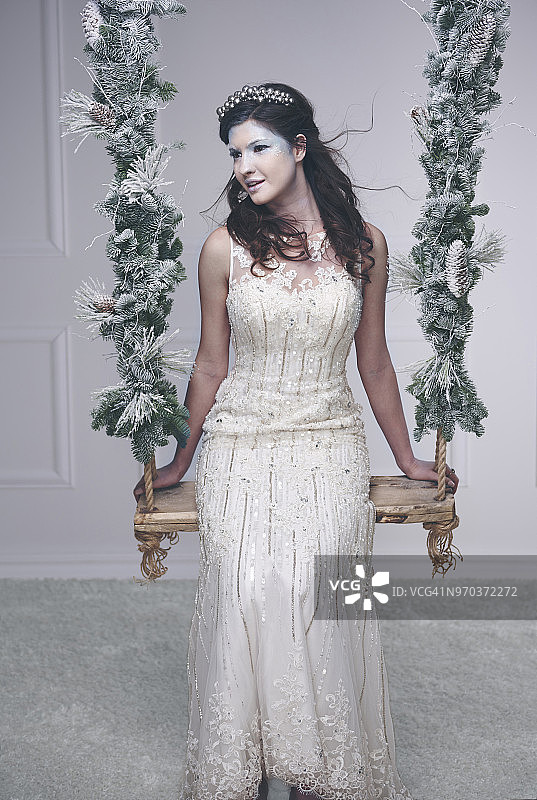 身穿白色连衣裙，化着冰妆，坐在秋千上的模特，波兰德比察图片素材