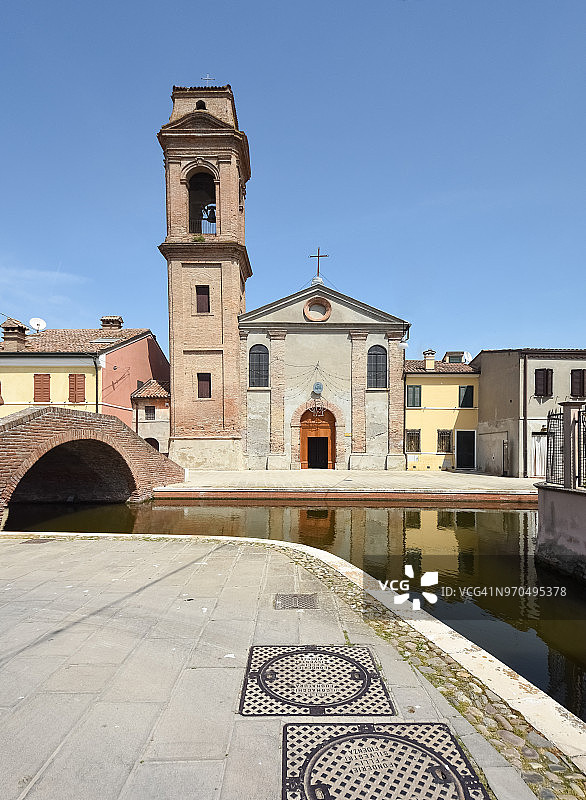 意大利艾米利亚-罗马涅地区威尼斯泻湖运河水域中,色彩缤纷的房屋和教堂立面倒影下的科马基奥古老中世纪城镇图片素材