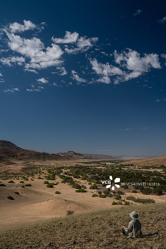 戴着狩猎帽的旅行者俯瞰纳米比亚Hoarusib河床图片素材