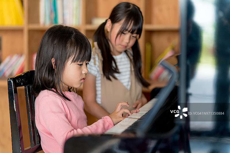 两个年轻女孩一起弹钢琴图片素材