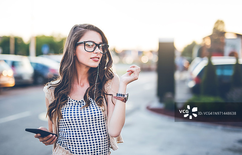 女人在户外用手机听着喜欢的音乐放松图片素材