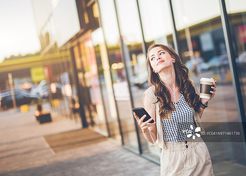 在户外享受音乐和咖啡的现代女性图片素材