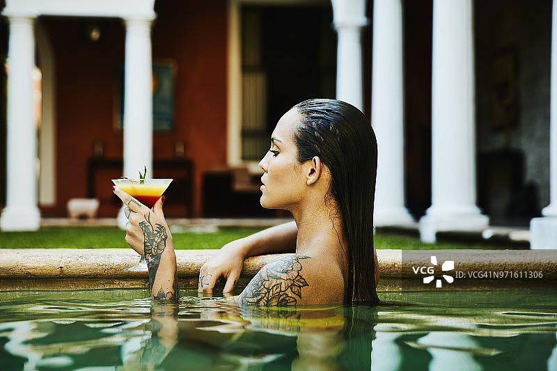 在精品酒店泳池放松身心，享受饮品的女人图片素材