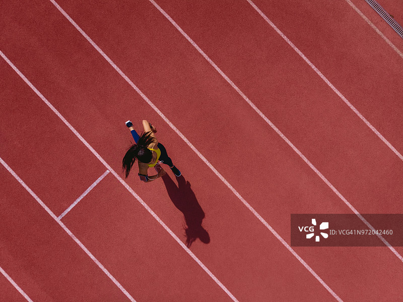 在运动跑道上听音乐跑步的女运动员图片素材