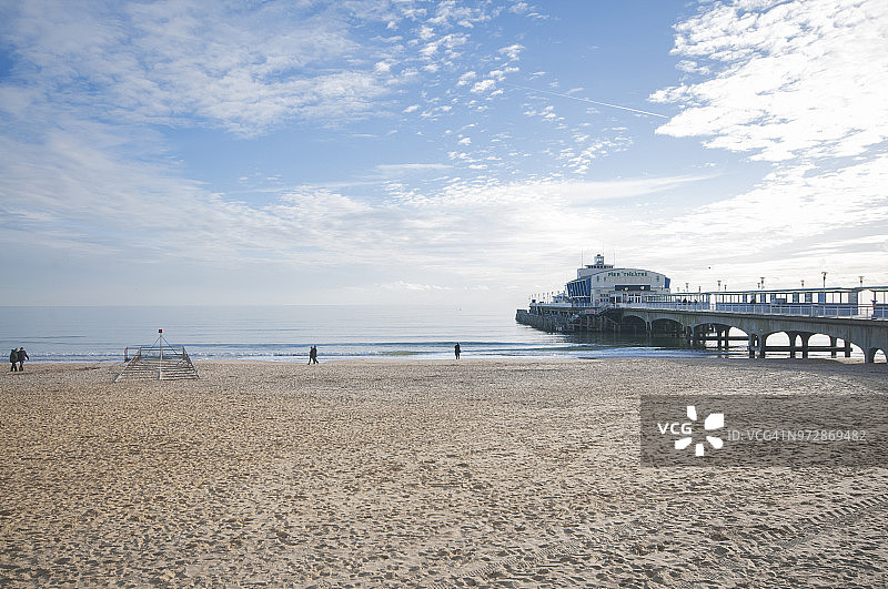英国伯恩茅斯：多云夏日里波涛拍打着沙滩和码头图片素材