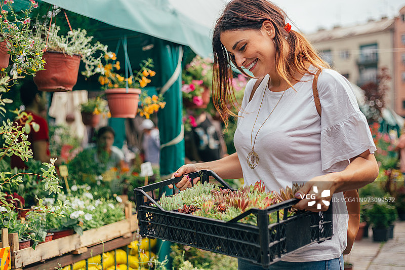 年轻漂亮的女子抱着一箱鲜花图片素材