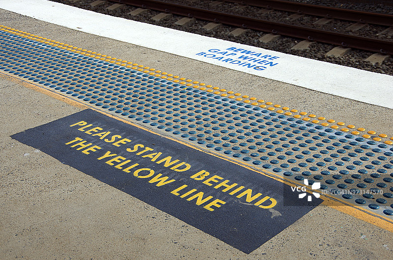 铁路站台上的“注意间隙”和“请站在黄线后”标志图片素材