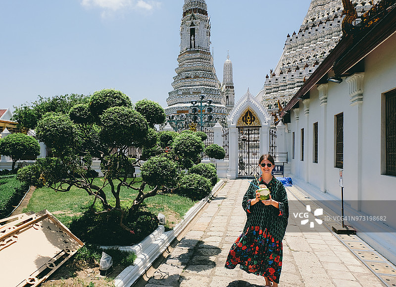 女子身穿连衣裙在曼谷郑王庙附近喝椰汁图片素材
