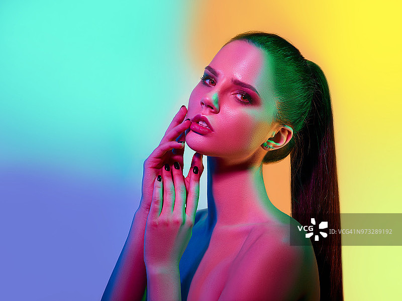 在演播室中以彩色灯光摆姿势的高级时装模特图片素材