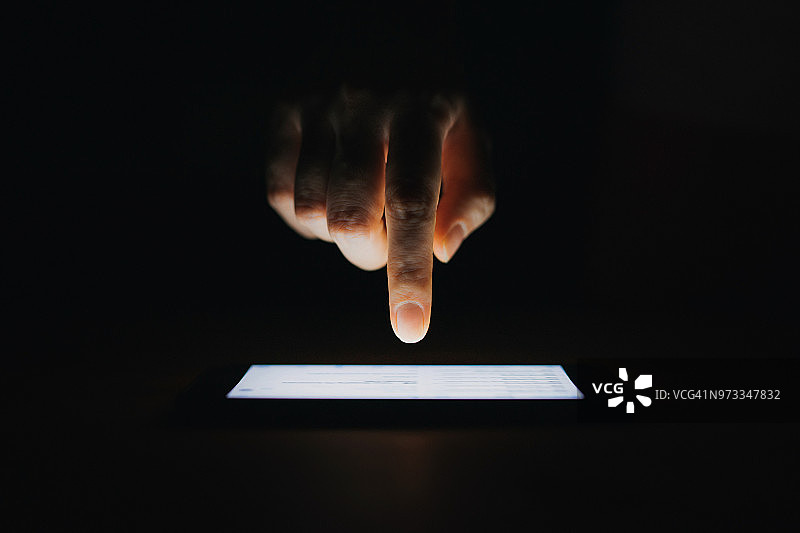 黑色背景下，女人用智能手机查看电子邮件的特写图片素材