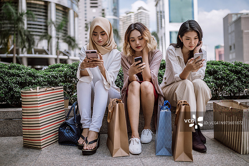 年轻女游客购物后使用手机图片素材